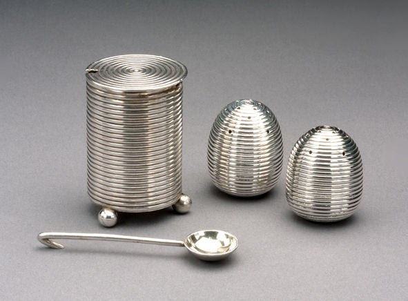 Made during the reign of Tsar Alexander III by the prominent Moscow silversmiths, Khlebnikov, the set comprises a pair of ovoid salt shakers, with a matching cylindrical moutardier and a parcel-gilt spoon. The top of each shaker is pierced and
