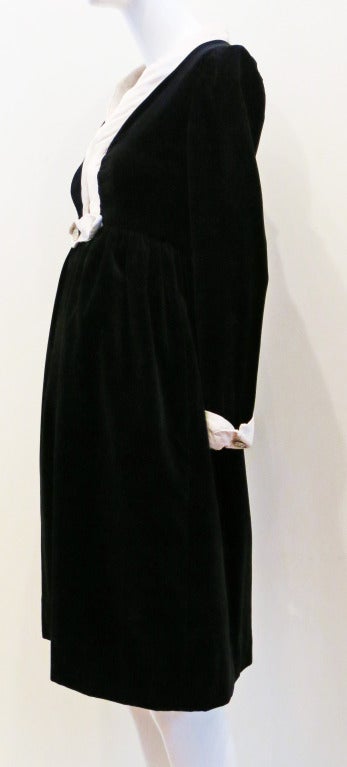 Black velvet long sleeve dress with v cut bodice. Three hook and eye closures above embellished double snap button closure at waist. Decorative rhinestone embellished buttons at each silk cuff. Hidden pockets on front of garment. Hand sewn hem.