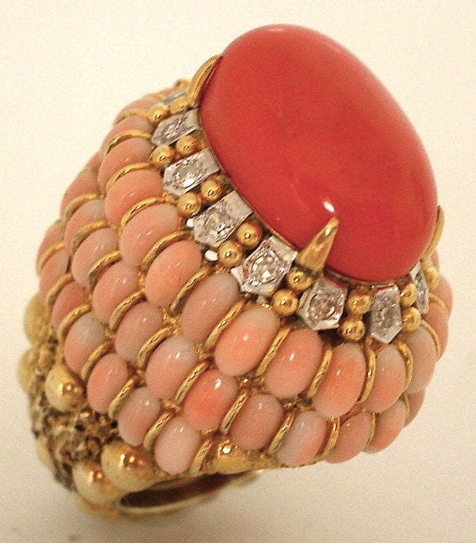 An elegant 18k yellow gold ,diamond and coral cocktail ring. The massive domed ring with a 20.5 x 13.3mm oval coral enhanced with round white diamonds and surrounded by three rows of small pink oval angelskin corals. This ring is stunning. The soft