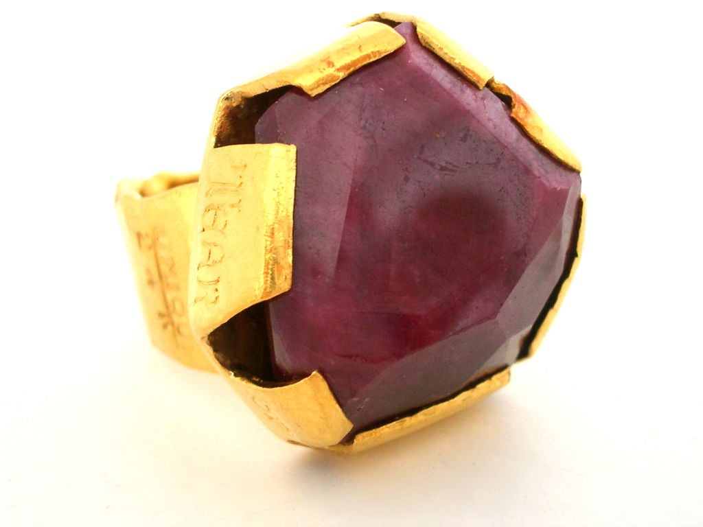 A brutalist high carat gold ring by Henry Alvin Sharpe. The wide band with numerous engraving and massive claw setting holding an unusual shaped 82.55 ct corundum , marked  : UNIQUE, 24K, HAS, Gold, Studio. On the back of the ring: H. ALVIN SHARPE,
