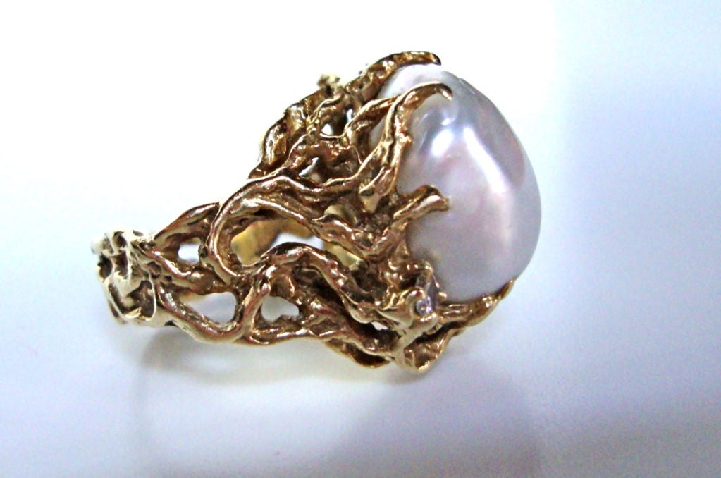 A stylish 18k yellow gold ,diamond and South Sea pearl ring by Arthur King. The organic, free formed gold ring set with a white baroque shaped south sea pearl, having good luster, enhanced with three round white diamonds. The top of the ring