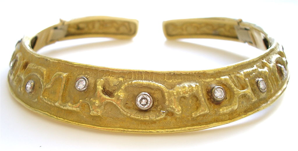 An elegant 18k yellow gold and diamond demi-parure attributed to the house of Mario Masenza. An 18k yellow gold repousse and chased graduated hinged collar with collet set round white diamonds and cross-over cuff bracelet designed in the same