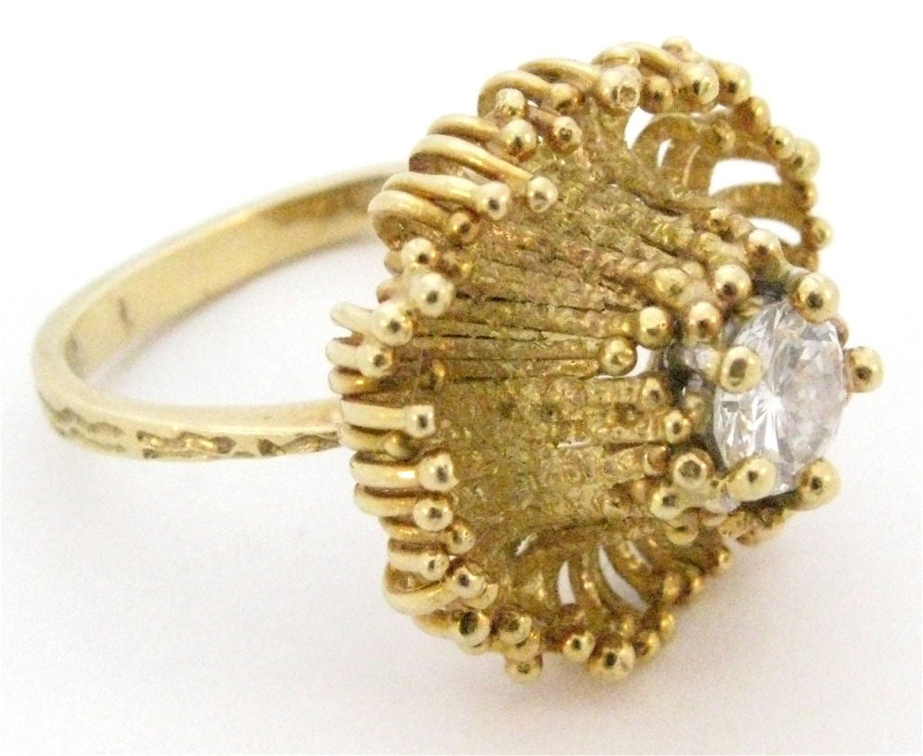 An attractive 18k yellow gold ring by Andrew Grima. The wirework ring in the shape of a stylized flower and set with a .70ct diamond. Pretty, Elegant and Unique. size 7.5