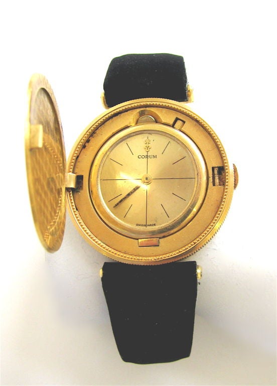 A handsome coin watch by Corum. The 18k yellow gold Double Eagle $20 coin, dated 1904, with a hinged opening that exposes a champagne dial, the watch with a Corum mechanical movement, numbered, on the original Corum black suede band. A clever and