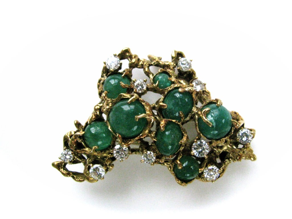 An attractive emerald and diamond pendant/brooch by Arthur King. The 2 1/4 long 18k yellow gold brooch in an abstract Freeform design with 11 round white diamonds weighing approximatly 2.00 cts and 8 bright green cabochon emeralds. A chic and showy