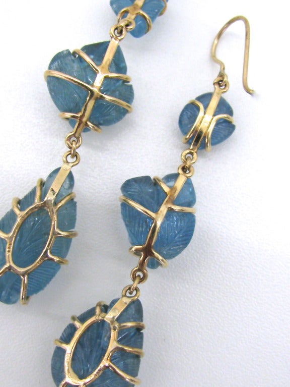 An Attractive pair of Aquamarine Earrings. The carved aquamarines in a leaf pattern, set in 14k yellow gold. Each aqua is slightly different in shape and size. One earring hangs 3 1/2