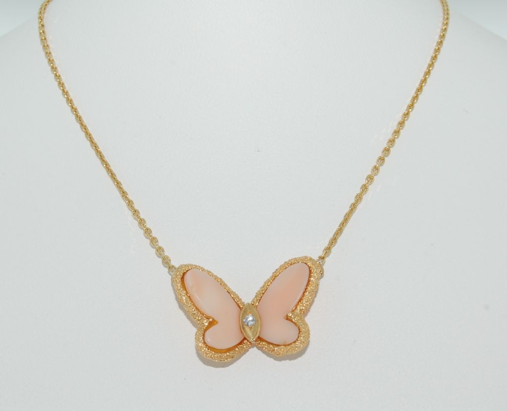 Vintage Van Cleef & Arpels Coral and Diamond Butterfly pendant necklace. The coral wings with diamond single stone body and textured border, attached to a belcher link chain and maker's tag with monogram mark (VCA) and number 72 122345 750.<br