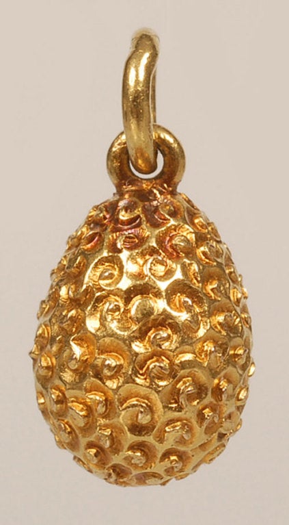 A Russian gem-set 56 standard gold miniature egg pendant, made in ST Petersburg prior to 1899, maker’s mark unclear. The repousse and textured body set with an oval cabochon sapphire. Height: 3/4