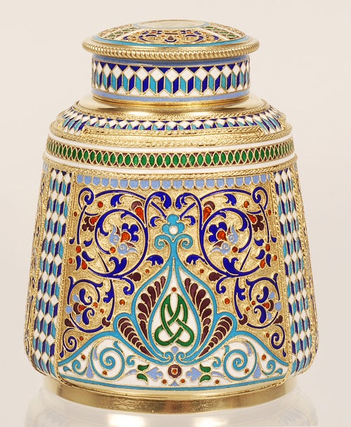 A Russian silver gilt and cloisonné enamel tea caddy, Antip Kuzmichev, Moscow, late 19th century. Of circular form with tapering sides, the caddy decorated with arched motifs containing scrolling foliate and geometric designs accented by green