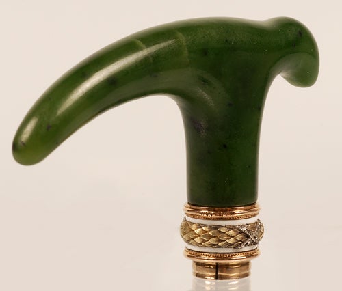A Faberge gem-set nephrite cane handle with two-color gold and enamel mounts, workmaster Henrik Wigstrom, ST Petersburg, 1908-1917. The collar with diamond-tied chased yellow gold laurel leaves between bands of white opaque enamel and rose gold.