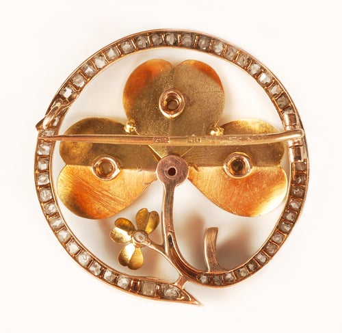 A Russian gold, gem-set and diamond brooch by Lorie. Formed as swirling clovers, the stem and petals set with diamonds, the center with a red gemstone. 1 1/4