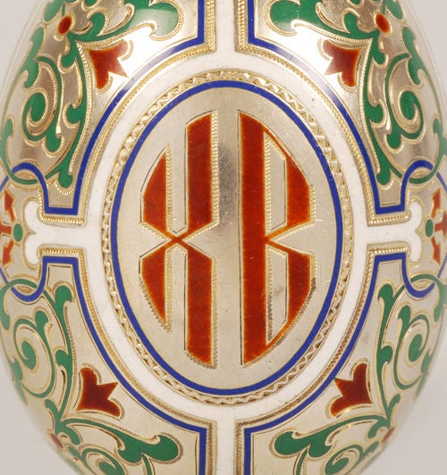 A Russian silver gilt and champlevé enamel egg, by Maria Adler, Moscow, circa 1890. Enameled in green, blue, red and white enamel in scrolling florals centered around an “XB” for 