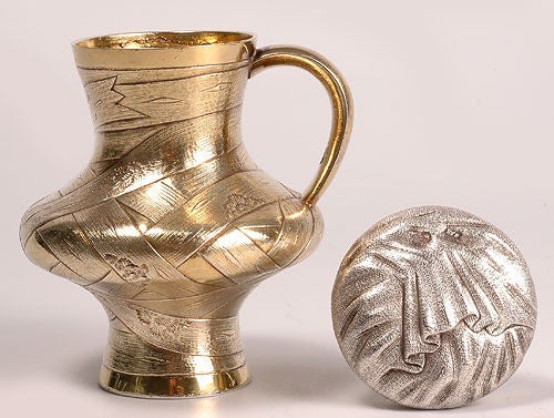 A Russian trompe l'oeil gilded silver jug, maker's mark unclear, Moscow, 1869. The jug is decorated in a gilded basket weave design with a silver trompe l'oeil cloth cap. Height: 4