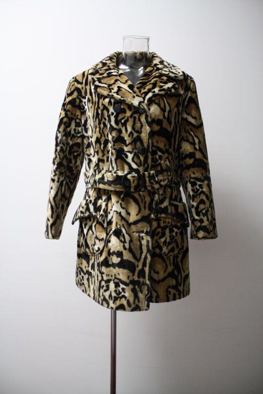 Gorgeous 1970's Modish Double breasted Faux Fur Coat in a very unusual crisp and bold Ocelot pattern. It's has a peacoat mixed with a mini trench coat style with a matching belt with an oval buckle. Fold over side pocket design and black qulited
