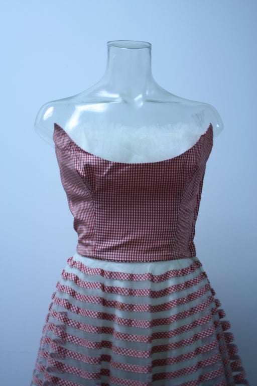 Beautiful Red and White Candy Striped Gingham dress boasts the architectural flair so present in post WWII fashions. The bustline is boned with a foldover peekaboo burst of white tulle. The skirt is a full ballerina circle with netted gingham