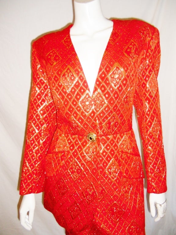 Stunning silk and wool brocade skirt suit. Red and gold with side flap pockets on jacket. Waistline of jacket features large gold hammered button with garnet center. 

Skirt has waistband, two side pockets, and a zipper closure.

Size