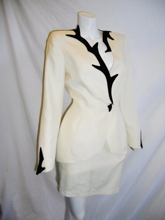 Never worn ivory silk skirt suit by Thierry Mugler . Black Velvet details.  Front waist snap closure covered in black suede. Retailed $3188. Circa 1988.  Skirt was shortened and same  fabric is still with suit that was never worn. Size 36. 
Bust