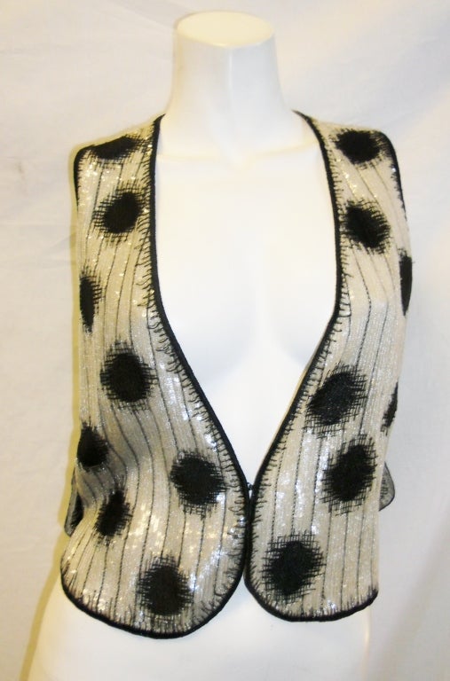 Incredibly beautiful Geoffrey Beene vest top. Clear  micro sequent on silver grey metallic silk. Black silk embroidery. Sides fastened with  two large crystal buttons. Front eye and hook closure. Pristine condition. Like new!!
Size 4-6
Bust (