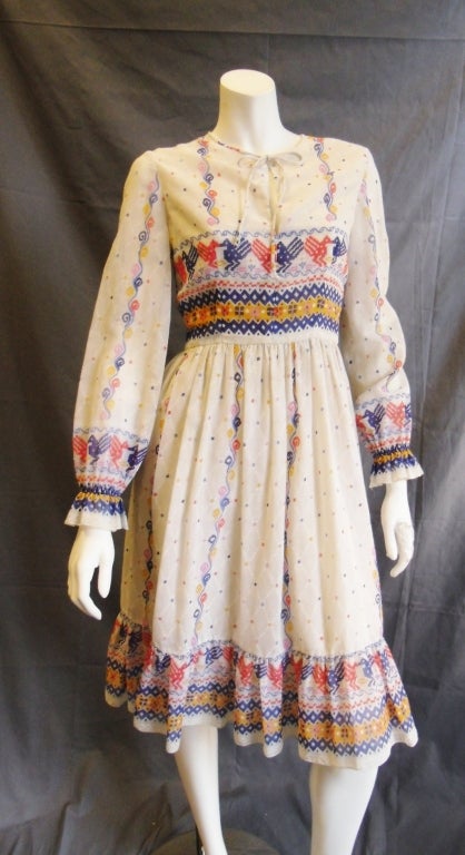 Fabulous early 70s vintage dress made by Oscar de la Renta as part of his “peasant look” line.  This dress is made of cotton poplin  and features a striking native motive in red , yellow and blue  colors. It has tapered waist, puffy sleeves that are