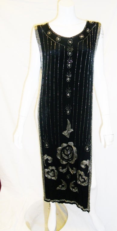In mint condition with all bead attached original Flapper overall cover dress. Held  aside with two silk strips. Silk over,  Silk lined and hand beaded with silver metal beads .Pristine condition.
Could be worn over dress or pants/leggings.