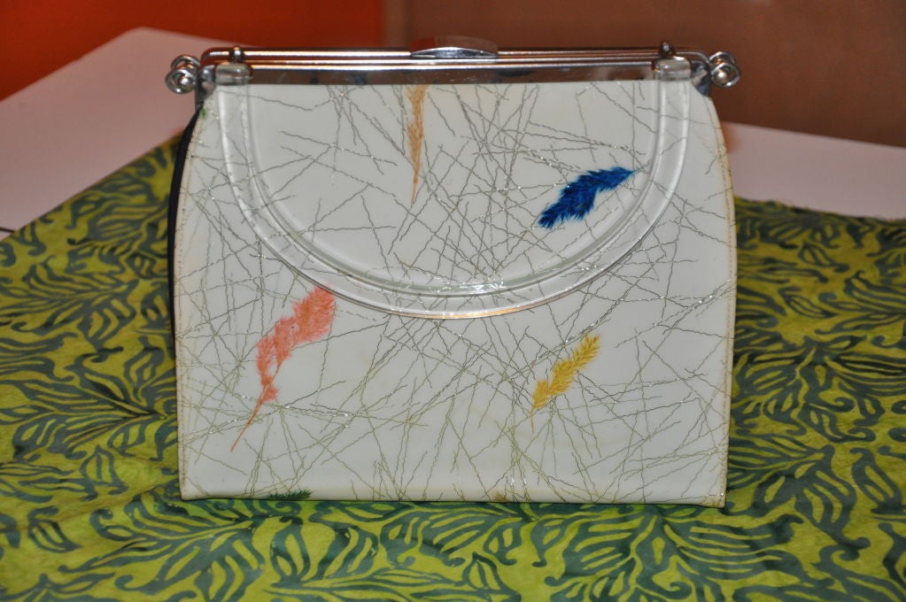 This extremely rare handbag can be changed into three different exteriors. The handbag has clear Bakelite. 1st, you have the option of having either a black-patent, or you can have a black silk bag, or for your festive side, a multi-colored