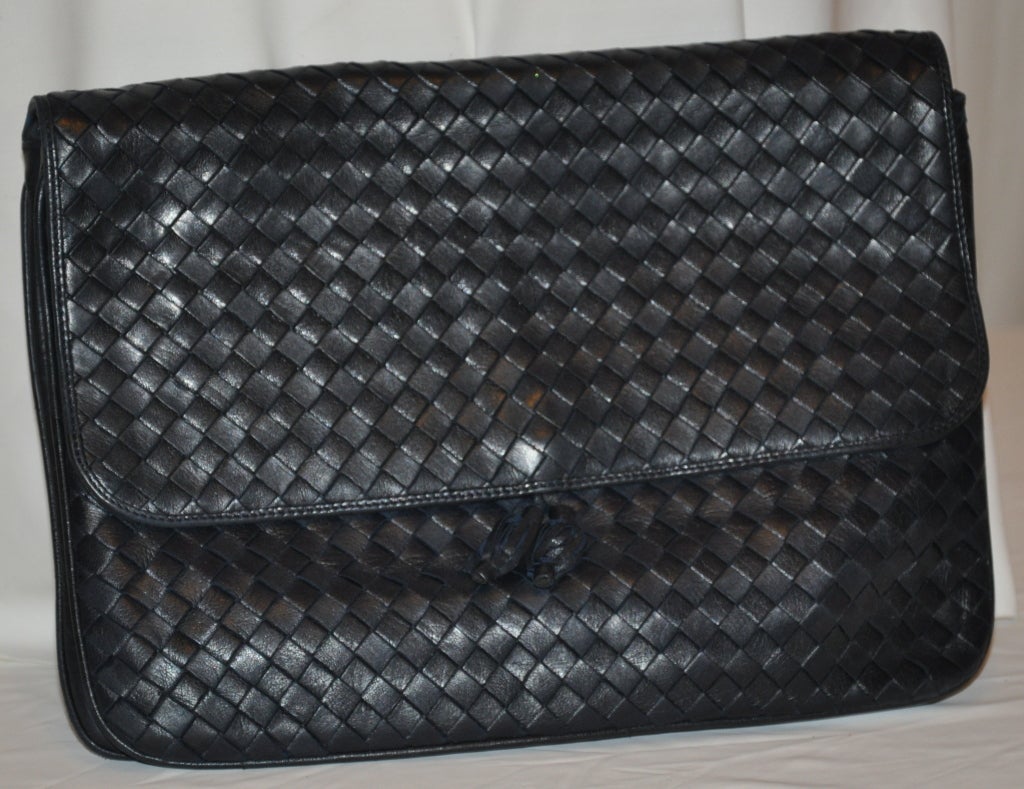 Peruzzi of Florence, Italy black woven lambskin leather clutch has a optional shoulder straps neatly tucked inside the bag. The bag has a large two-sectional along with a zipper compartment. The bag is fully lined and measures 9" in height,