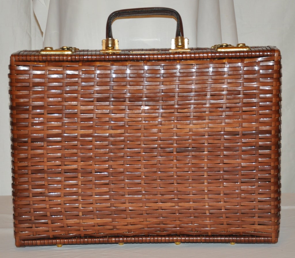 Brown wicker-style plastic briefcase made for Bergdorf Goodman has gold metal hardware detailing. The bottom of the briefcase has leather along with eight gold metal hardware feets to assure better wear. 
   The handle of the briefcase is out of