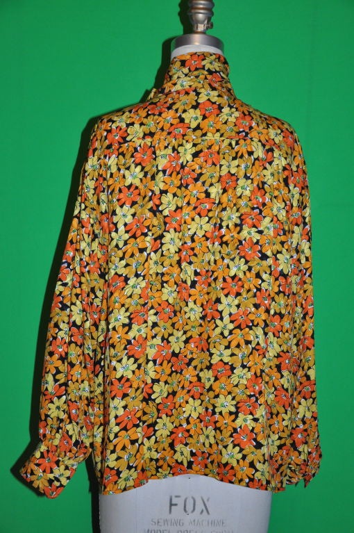 This Multicolored Yves Saint Laurent Floral blouse are in shades of tangerines, yellows, greens & golds on a black backdrop. The material is French crepe de chine. The neck has a extended 