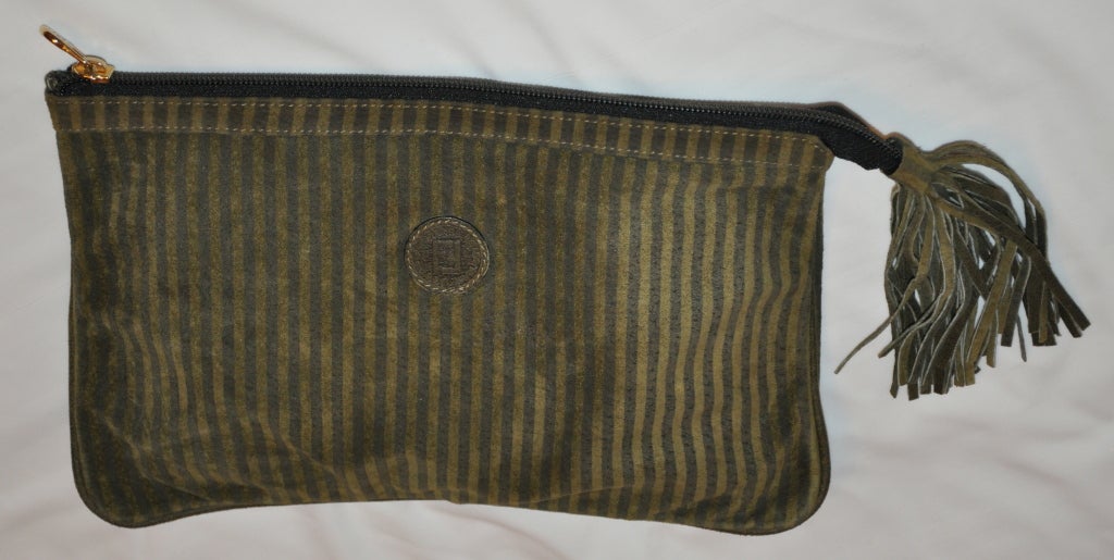 Fendi reversible clutch has one side stripe with their logo in suede and the other side in olive leather. The clutch is accented is a tassel which measures 5