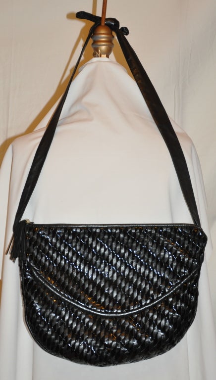 Shoulder bag woven with a combination of both black lambskin and black patent leather. The bag has a zipper top accented with a tassel attached to the zipper. The bag is fully lined and gold hardware accents.
  The straps measures 39