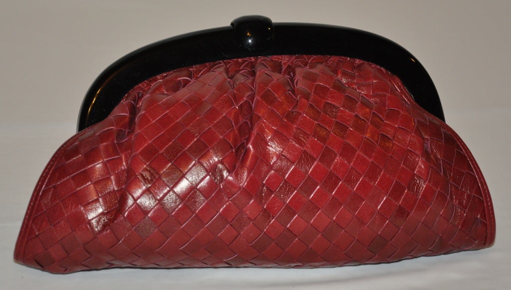 Limited Edition Bottega Veneta woven lambskin leather clutch is combined with hues of deep-red and burgundy strips of color. The Lucite frame has a 