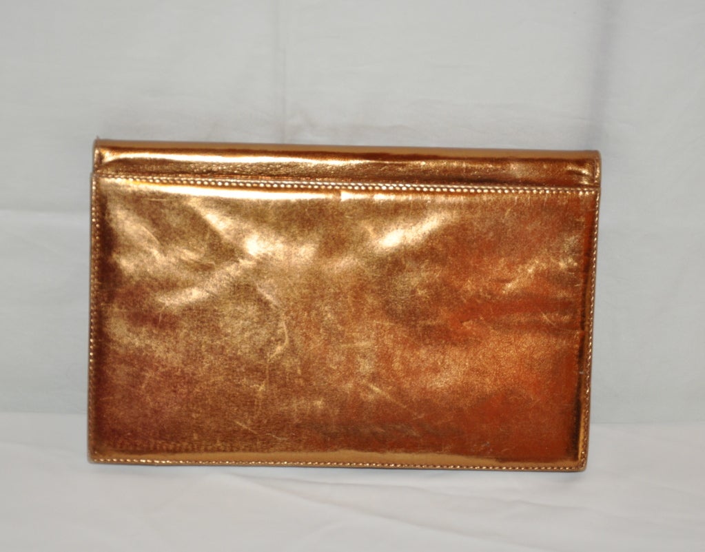 Saks Fifth Avenue's Metallic Bronze calfskin envelope clutch and shoulder bag is fully lined with beige calfskin. There's a zippered compartment within the interior.
   The shoulder strap is of gold tone hardware which can be removable if desired