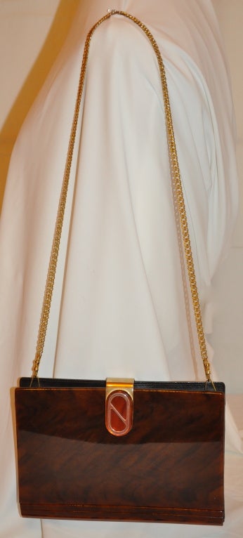 IPES's brown lucite with gold hardware clutch can be also used as a shoulder bag if desired. The removable gold hardware shoulder straps measures 16 1/4