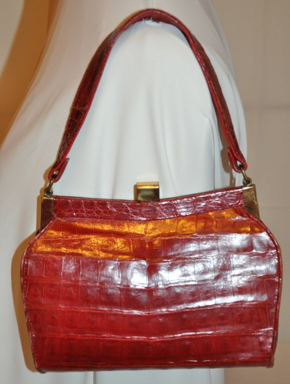 Deep-Red Alligator with gold hardware handbag is fully lined and comes with a attached change-purse and double-sided mirror.
   The handbag measures 6