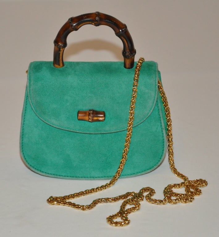 Gucci Minaudiere classic in green suede with bamboo handle and clasp closing. One of Gucci's most classic, you have the option of a handbag or, with the heavy detachable gold hardware chain located inside, one can also wear as a shoulder bag.
  
