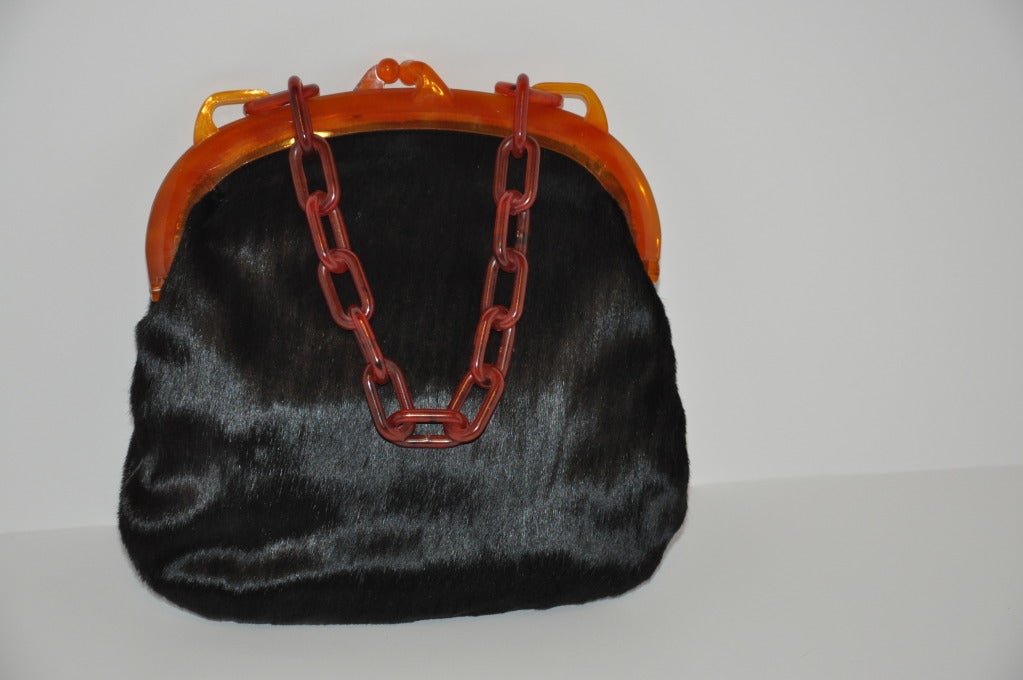 This wonderful Koret Lucite and Pony Handbag and a change purse attached onto the front of this bag. The interior is lined with black leather highlighted with tan leather within the open compartment for contrast. The bag measures 10