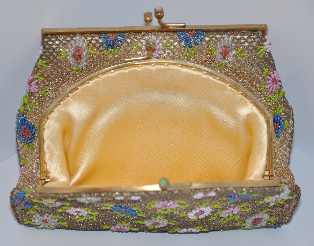 Brooks multicolored double-purse has micro-sized seed beading throughout. Hand-beaded in France, patterned with multi-colors of florals. Both purses are attached and fully lined with golden silk-satin. Both opening clasps are accented with