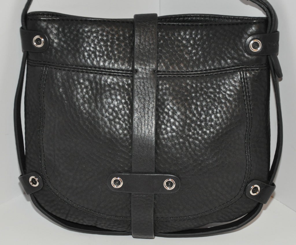 DKNY's textured black calfskin shoulder bag has wonderful top-stitched detailing along with silver hardware throughout the bag. Opening has a flap-over leather strap along with silver hardware which slips into a belt-like strap, and secured by a