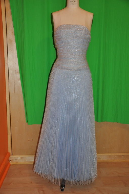This Randolph Duke powered blue strapless gown is surprisingly weightless and flows effortlessly. The powered blue is covered in 'candy-striped' paper-thin clear plastic-like material. This gown is strapless and backless. The center back zipper has