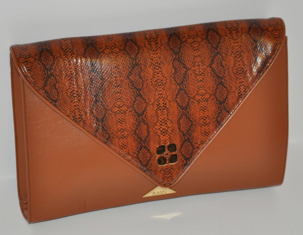 Iman, one of the iconic models of the '80s, brings her style and taste to the styling of this wonderful huge clutch. Rich hues of browns with it's snakeskin print leatherette flap makes for a great day bag to hold all your needs.
   Clutch measures