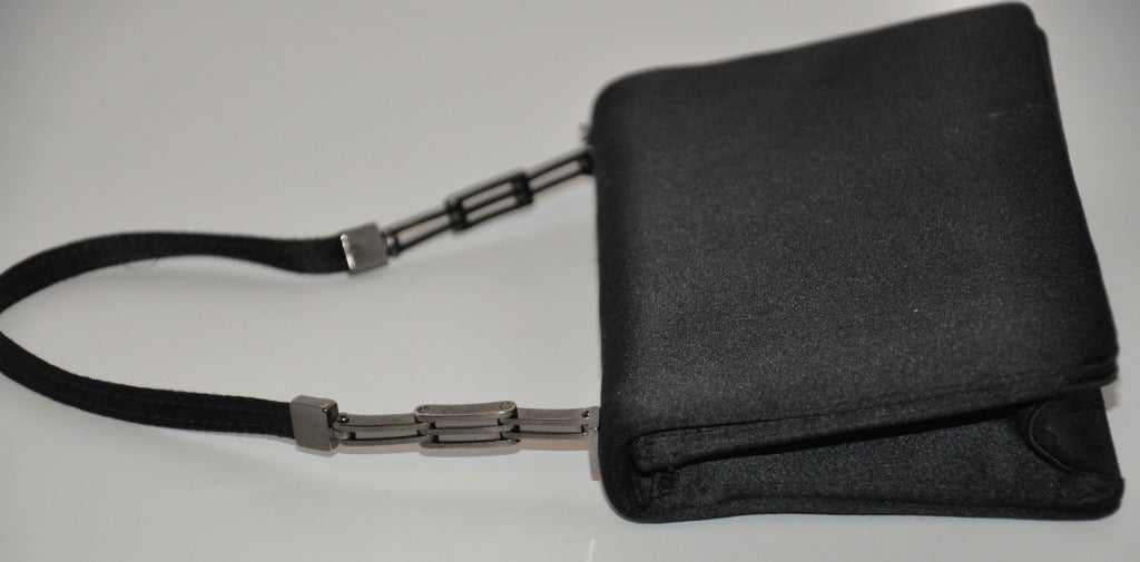 Giorgio Armani black minaudiere evening handbag of silk jacquard, and fully lined on the interior with the same. There's a mirror attached to the inner flap for a quick check if needed. The handle are accented with silver hardware. height of handle