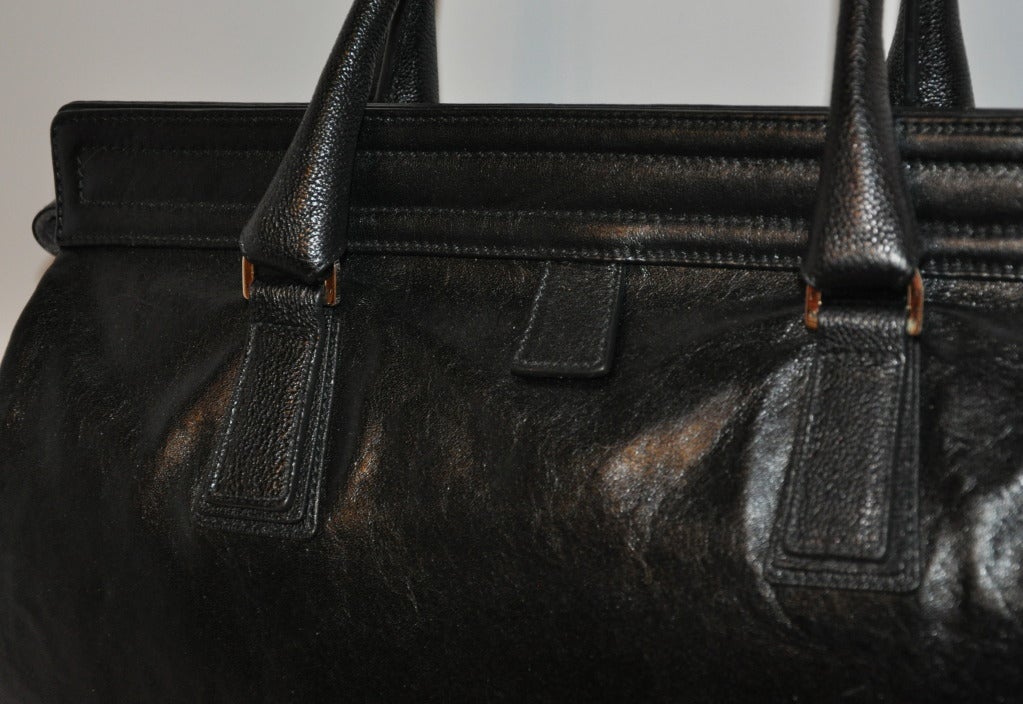 Black calfskin leather has two magnetic tabs along the top opening. There are also two tabs for handling when opening the 