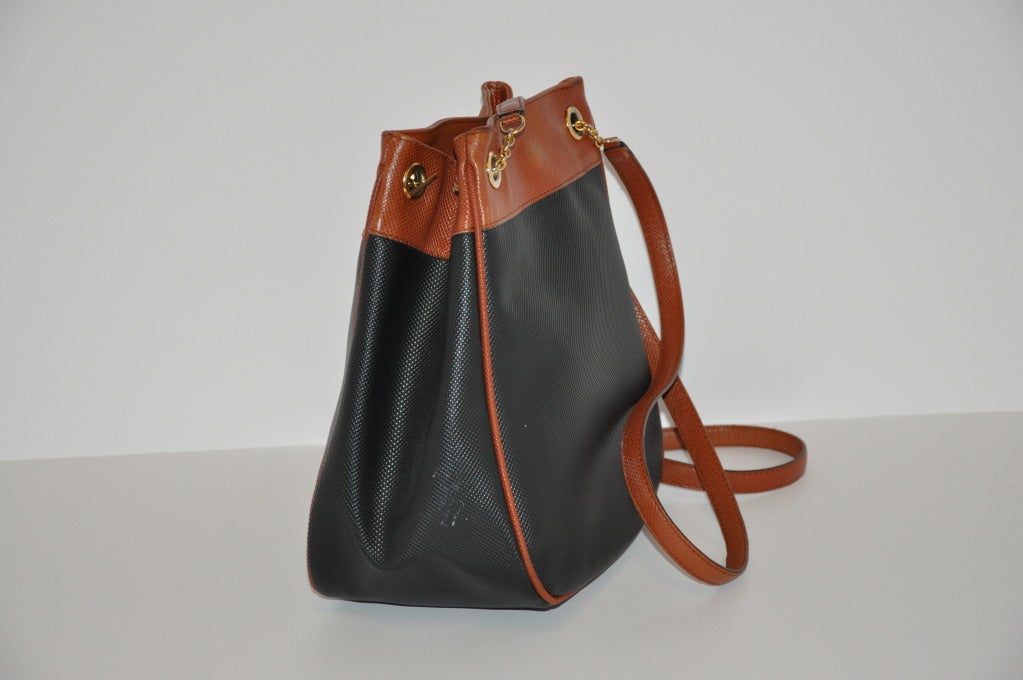 Bottega Veneta black & brown top-grain calfskin leather has brown top-grain leather piping throughout the bag. There's a outer open compartment on one side and the interior has a zippered compartment. Bag is highlighted with gold hardware and a
