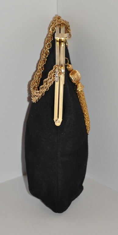 Black calfskin suede evening bag is accented with gold hardware and adjustable gold hardware chain-straps. Straps can be worn double-handle or single with one resting on the frame. Frame has gilded gold panels and highlighted with a tassel in