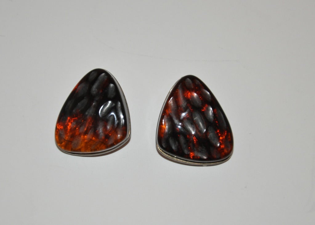 These earrings of silver hardware and poured glass inlaid are multi-colored in browns, golds and black depending on how the lights reflects. Measurements are 1 2/16" in height, 7/8" in width and 7/16" in depth.