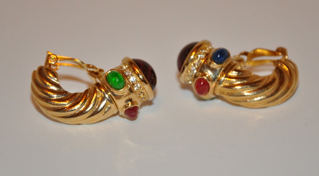This large gilded gold hardware clip-on earrings are accented with multi-colored faux cabochon stones. Earrings measures 1 1/2