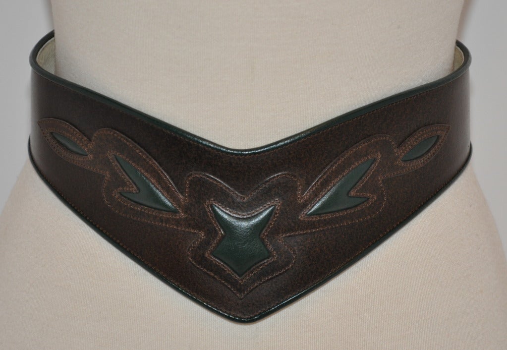 This wonderful brown calfskin leather belt is detailed with top stitching and highlighted with green patches of leather and matching green leather piping on the edges. This belt can be worn with the front pointing upward or downward. Buckle is