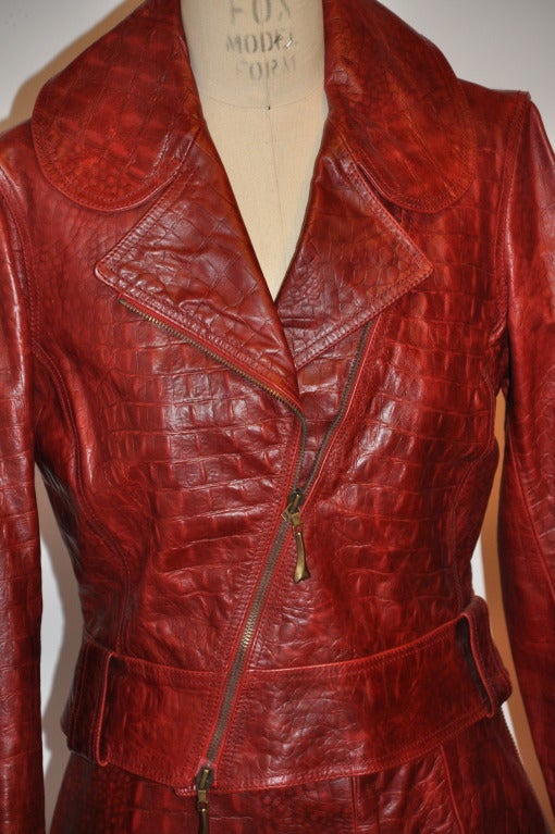 Robert Cavalli burgundy embossed crocodile leather is highlighted with lycra panels hidden within the seams for a excellent form-fitting fit on the skirt. 
   The motor-cycle style jacket has a two-way front zipper of 16