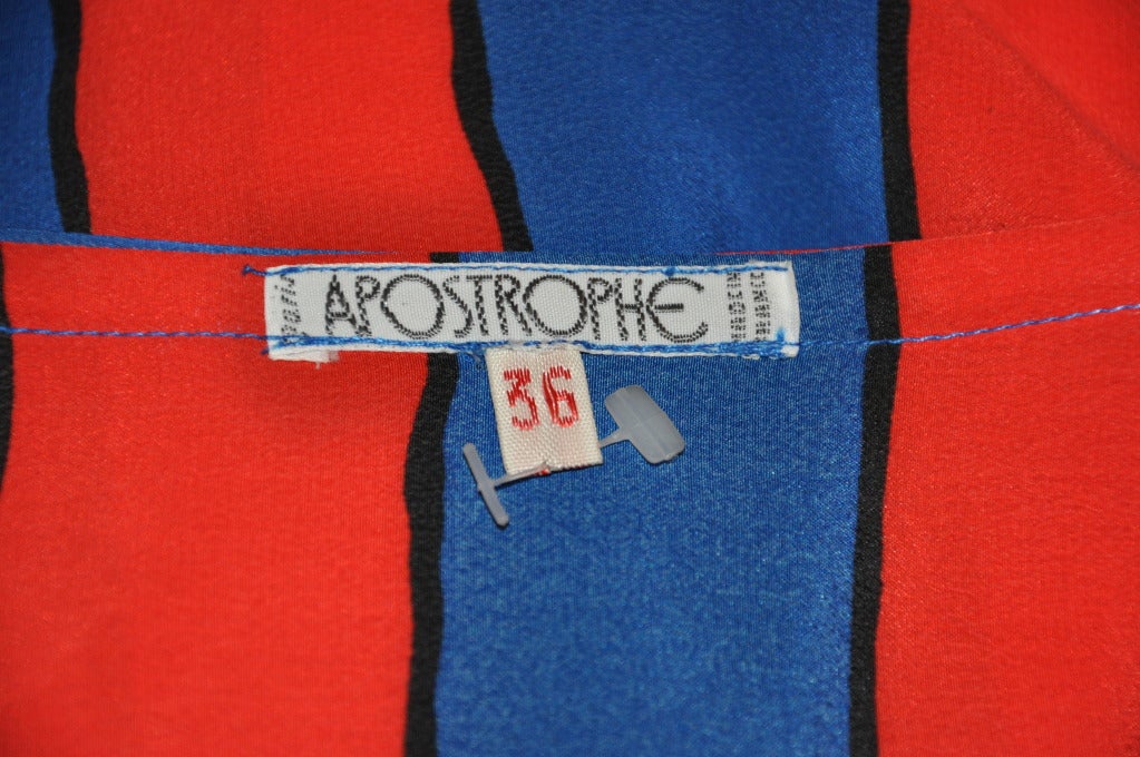 Apostrophe's silk tunic in colors of blue and red is highlighted with thin black stripes. Tunic has two side slits measuring 9 1/2