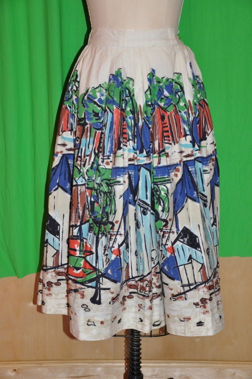 This cotton circular skirt has a wonderful print, bright and colorful. Along the waistband, there are sections of folded pleating, mainly along the backside. The waistband has a single button. The skirt length is 28 1/2